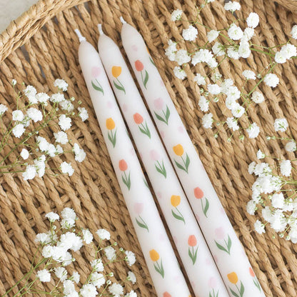 Tre tulpanmönstrade ljus på flätat underlag med små blommor