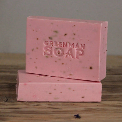 Två rosa Greenman-tvålbitar staplade på ett träbord