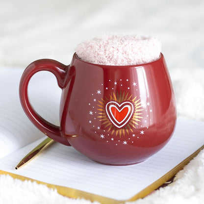 Sacred Heart-mugg med rosa strumpor på en anteckningsbok
